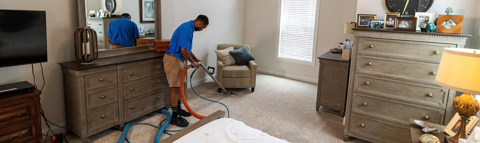 A man cleaning the carpet using a vacuum equipment.